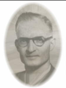 A black-and-white oval portrait of an older man with short hair and glasses, wearing a suit and tie. The photo has a soft-focus effect, giving it a nostalgic and vintage feel.